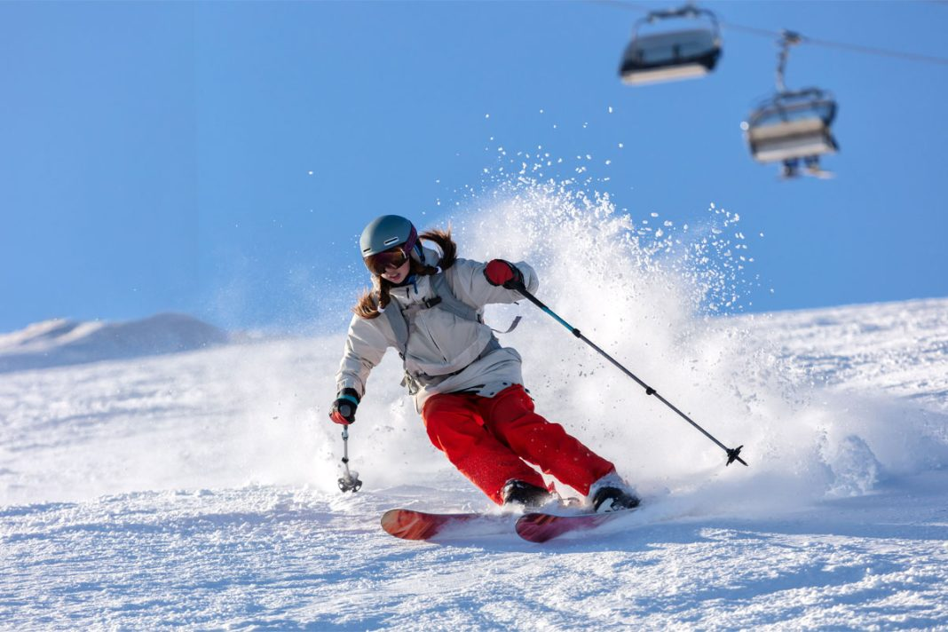 Skieuse dévalant une piste enneigée sous un télésiège